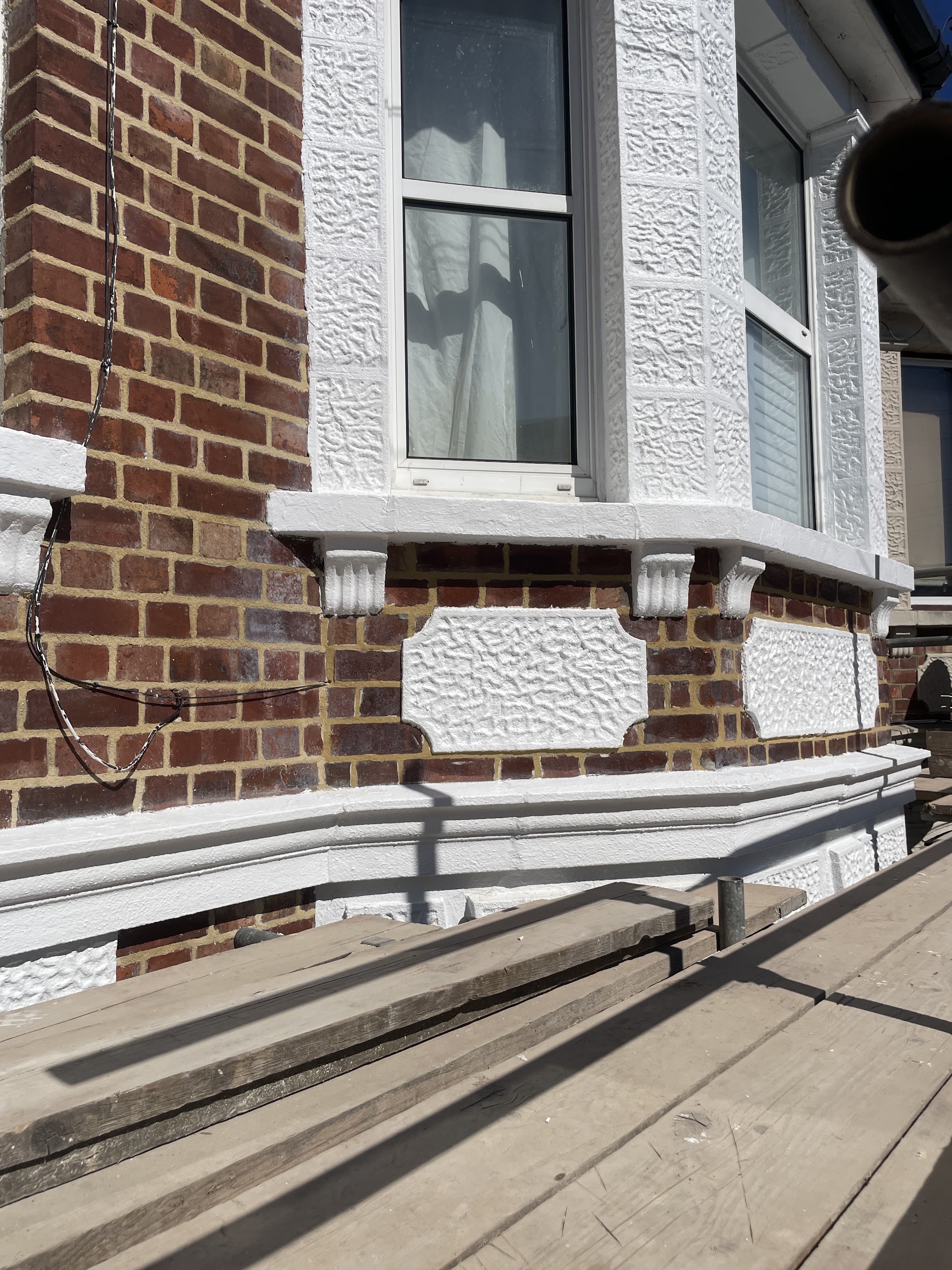 Repointed red brick beneath an ornate Victorian bay
